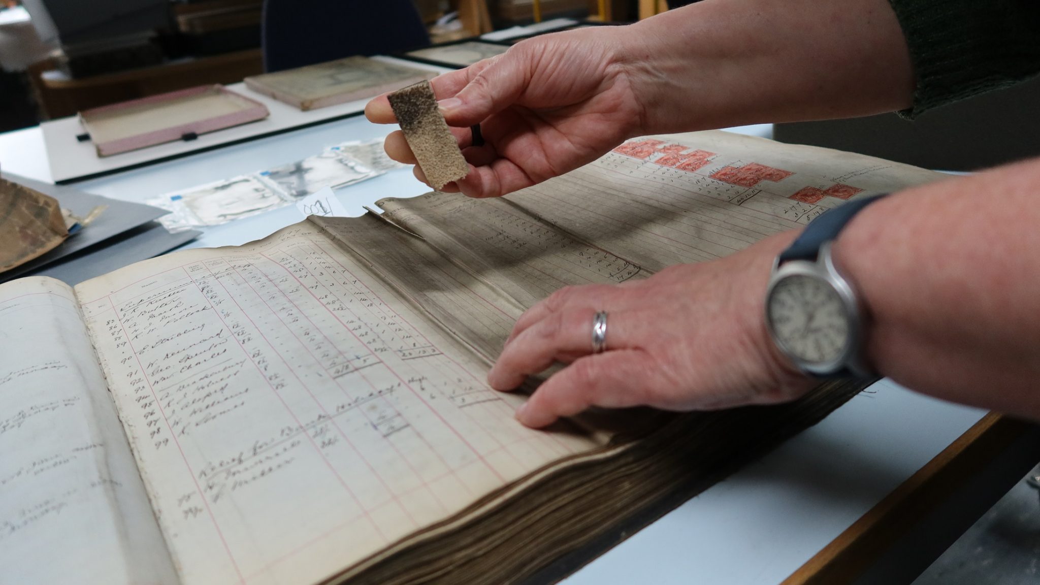 Cleaning surface dirt off the pages of a ledger of Tower Bridge staff