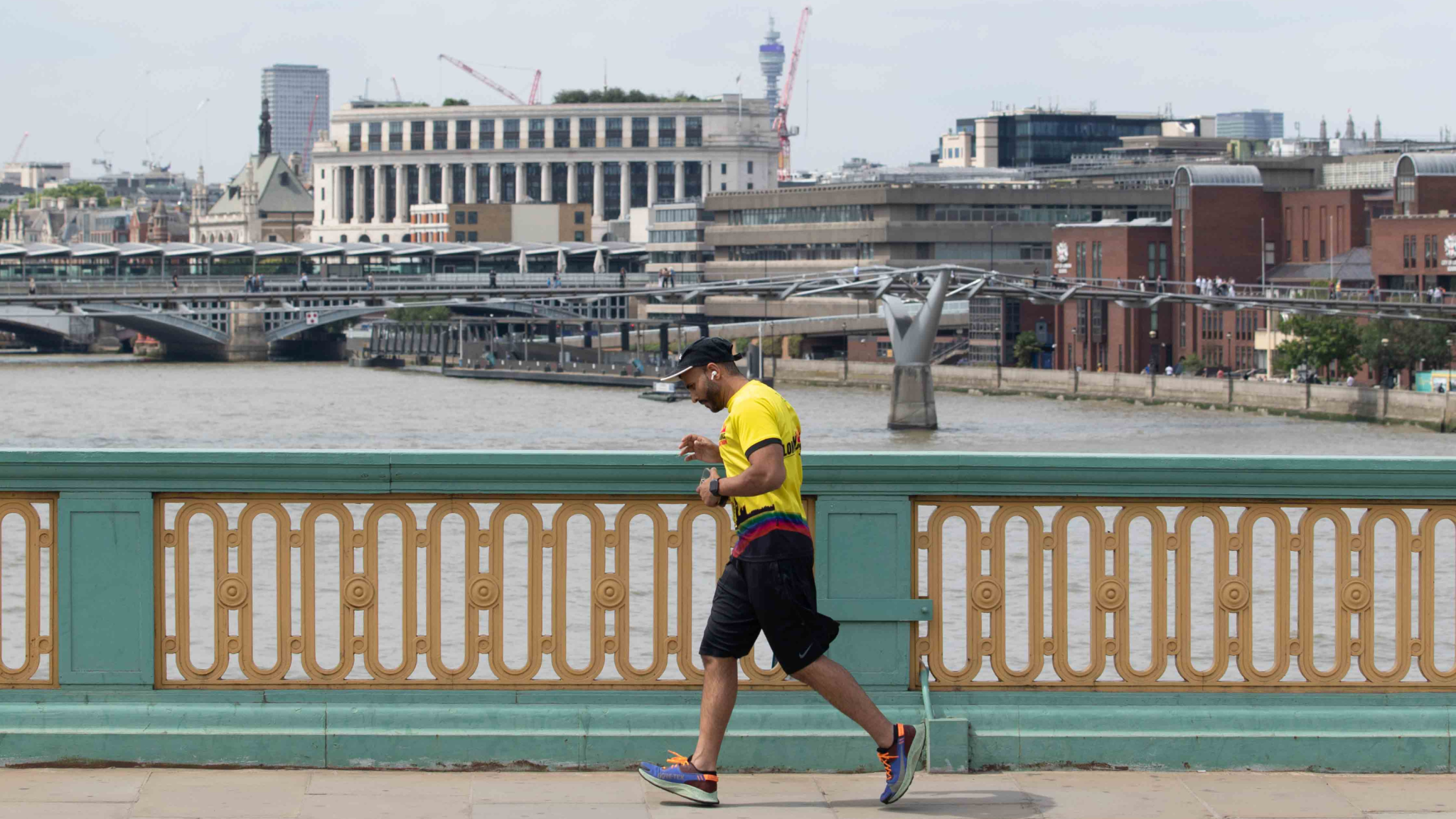 A jogger runs across Southwark Bridge, with the river and Millennium Bridge in the background.